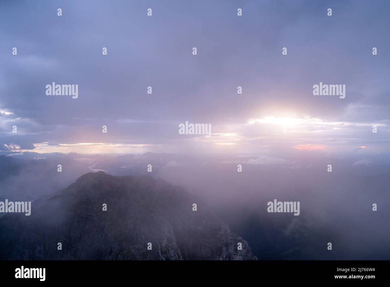 Der zweite Gipfel des Guffert liegt bei Sonnenuntergang zwischen Nebel und Wolken unerreichbar. Es führt kein offizieller Weg dorthin und dank Regen, starken Winden und Einbruch der Dunkelheit kann er nur vom Gipfelkreuz aus beobachtet werden. Stockfoto