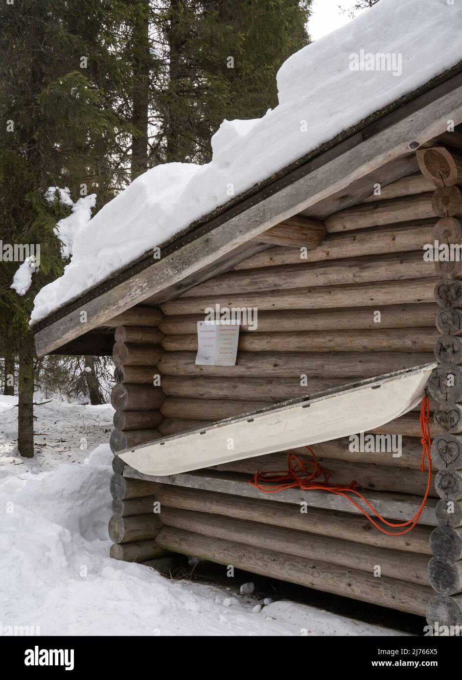 Rovaniemi, Finnland - 19.. März 2022: Ein Rettungsschlitten an der Wand einer Blockhütte in einem verschneiten Wald in Finnland. Stockfoto