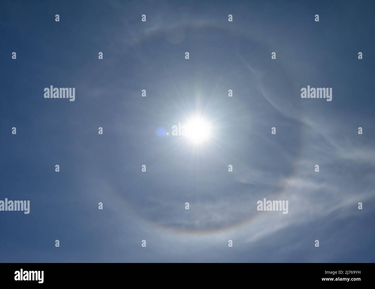 Optisches Phänomen, das als 22-Grad-Halo um die Sonne bezeichnet wird. Eiskristalle in der Atmosphäre brechen Licht und erzeugen den Halo. Stockfoto