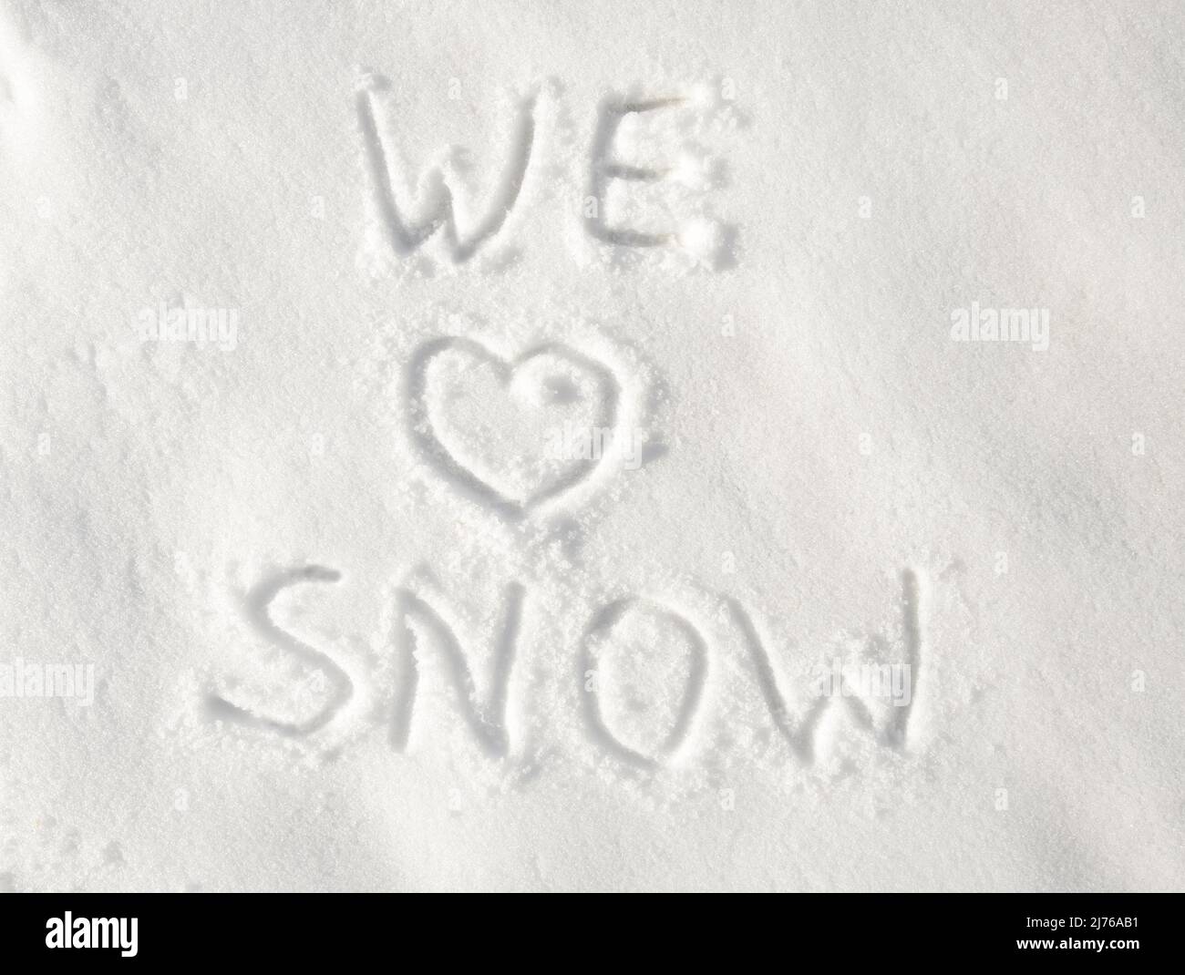 Text „Wir lieben Schnee“, geschrieben in Schnee; mit einem Herz für die Liebe Stockfoto