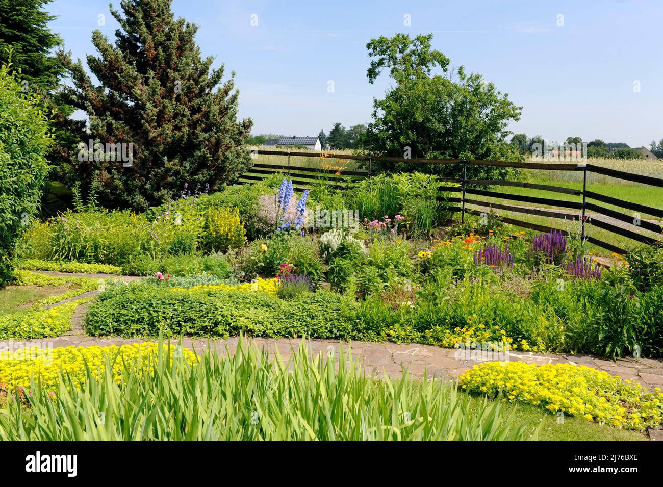Landhaus-Garten mit farbenfroher Sommerflora, eingerahmt von verschiedenen Wäldern Stockfoto