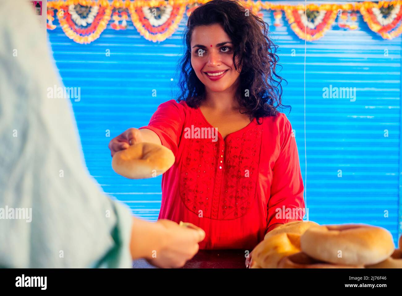 Glückliche indische Hündin salling frische traditionelle Brötchen im Basar Stockfoto