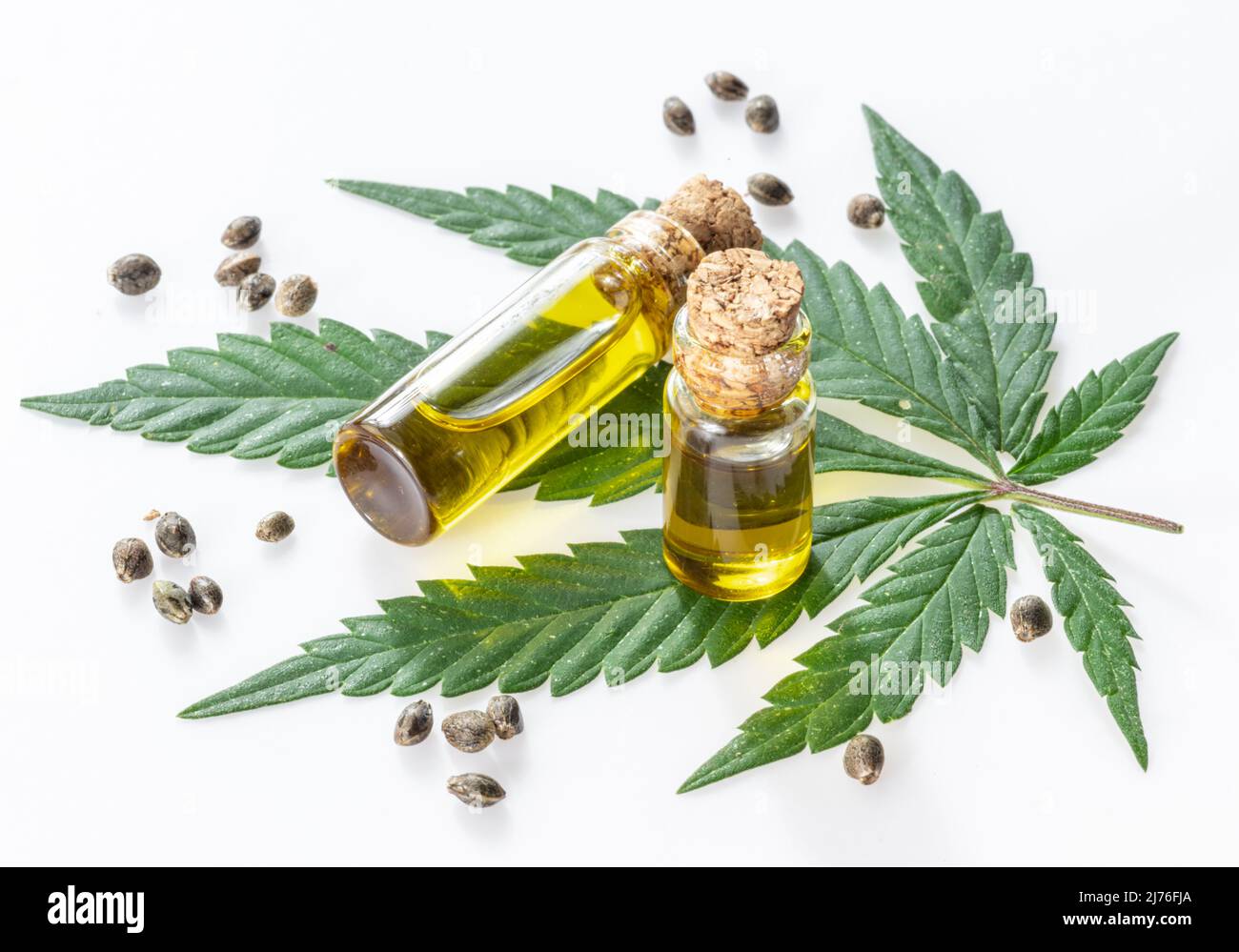 Cannabisblatt und kleine Flaschen Hanföl isoliert auf weißem Hintergrund. Nahaufnahme. Stockfoto