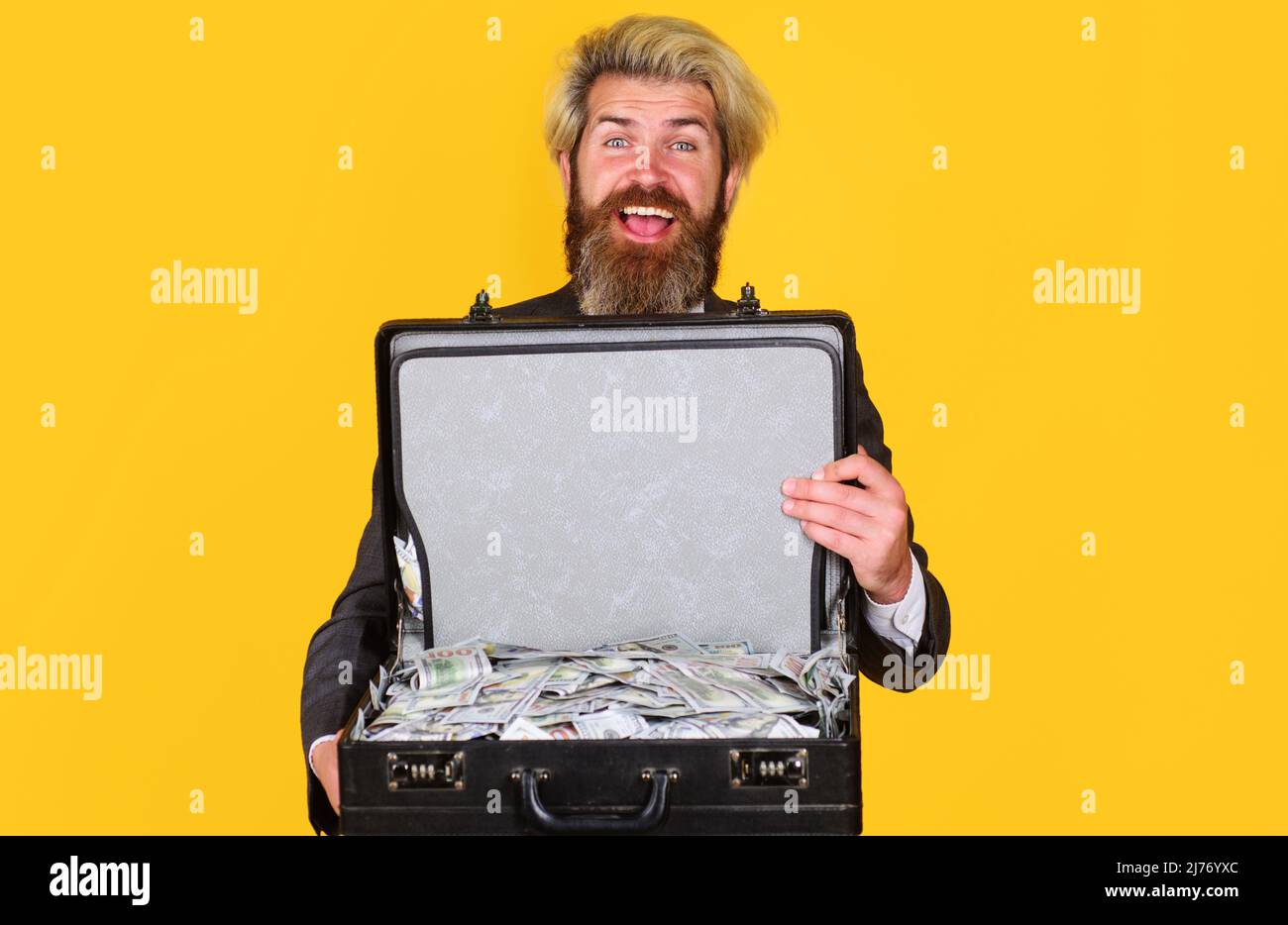 Glücklicher Geschäftsmann mit Aktentasche voller Geld. Bärtiger Mann mit Dollarfall. Leihservice. Stockfoto
