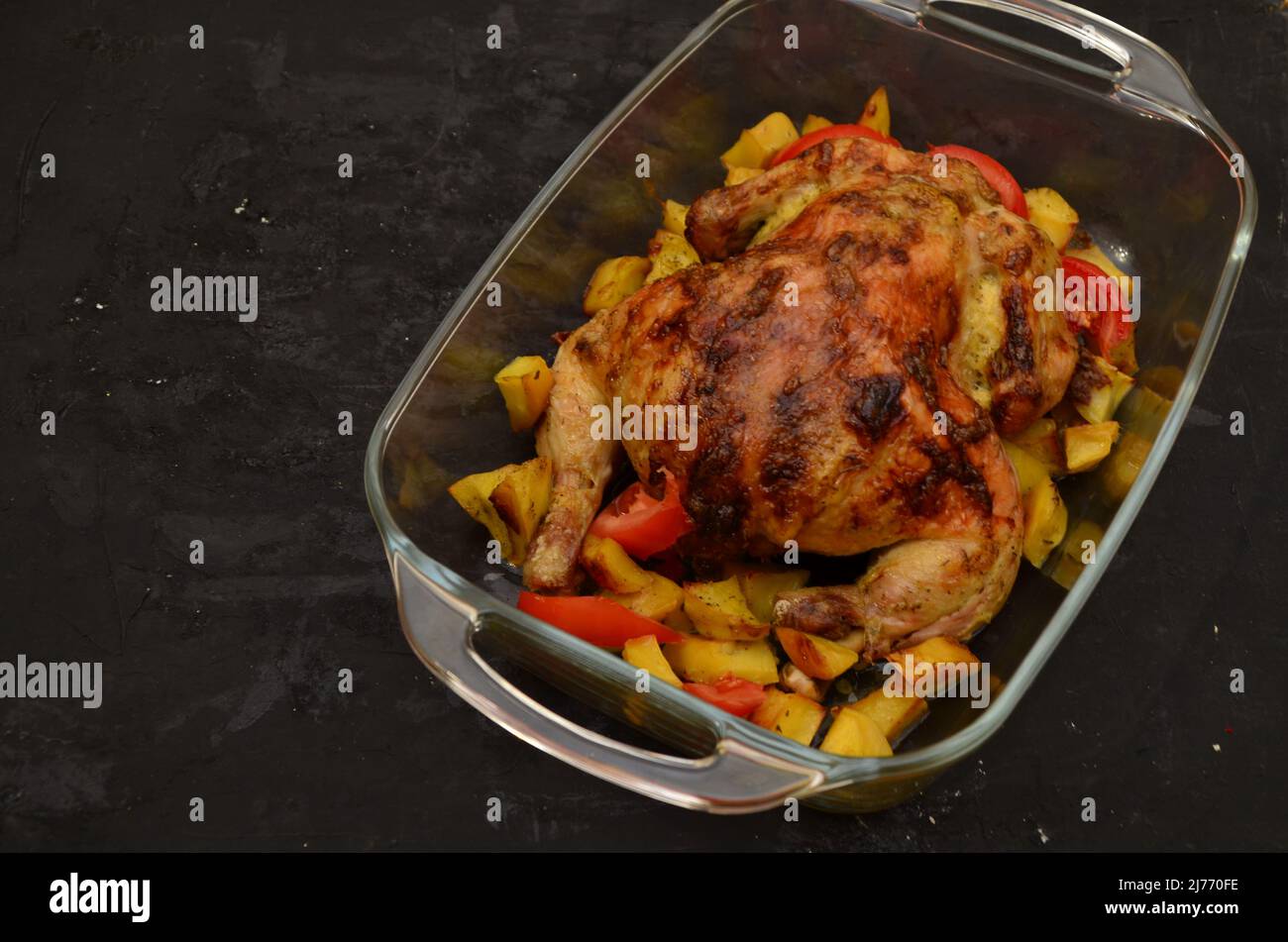 Gebratenes Huhn oder gegrillter truthahn zu Weihnachten oder Thanksgiving in Sauce mit Kartoffeln, Gemüse und Rosmarin in einer transparenten Backform auf einer dunklen Stockfoto