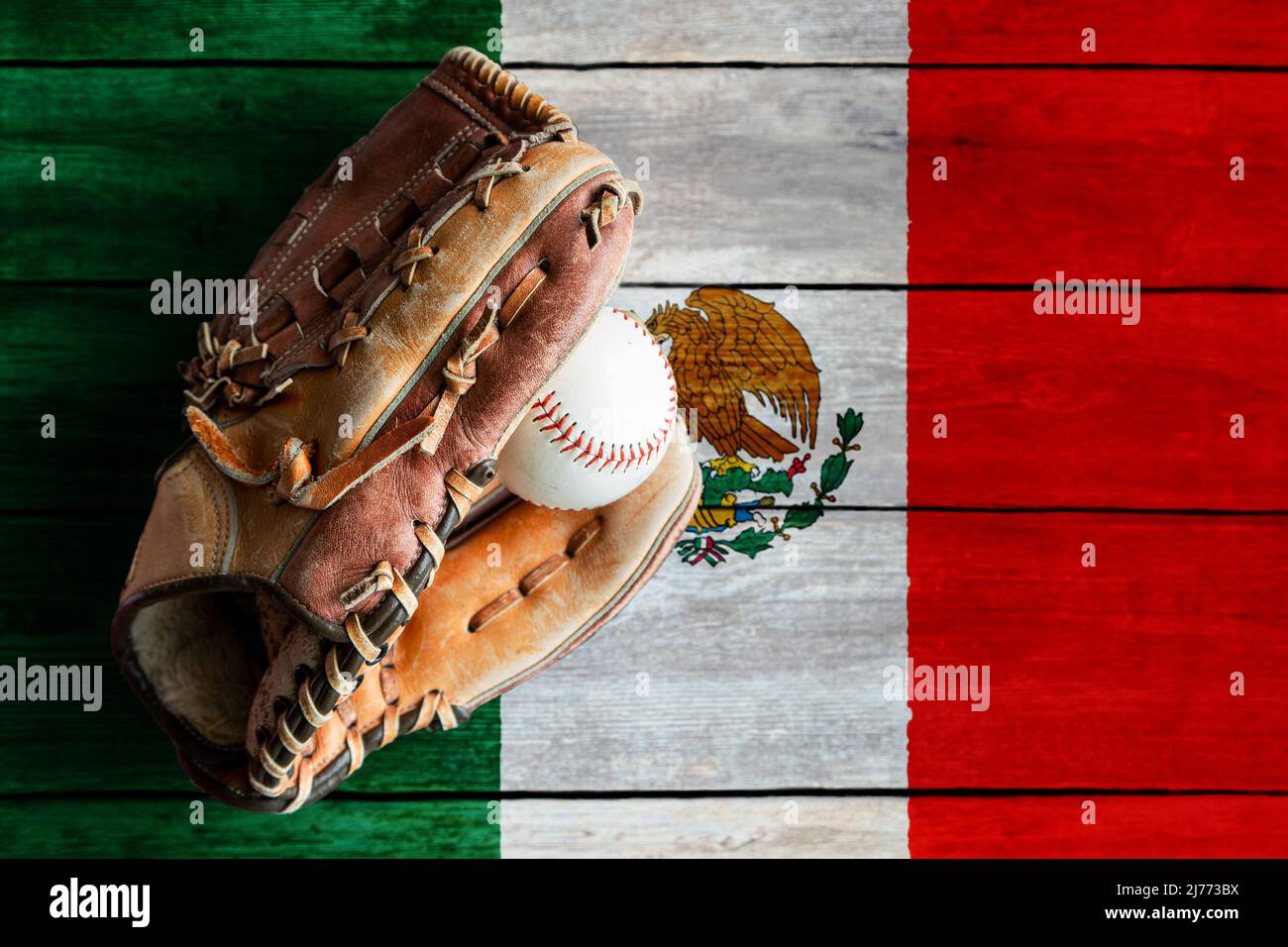 Baseballhandschuh aus Leder mit Ball auf rustikalem Holzhintergrund mit bemalter mexikanischer Flagge und Kopierraum. Mexiko ist eine der besten Baseballteams der Welt Stockfoto