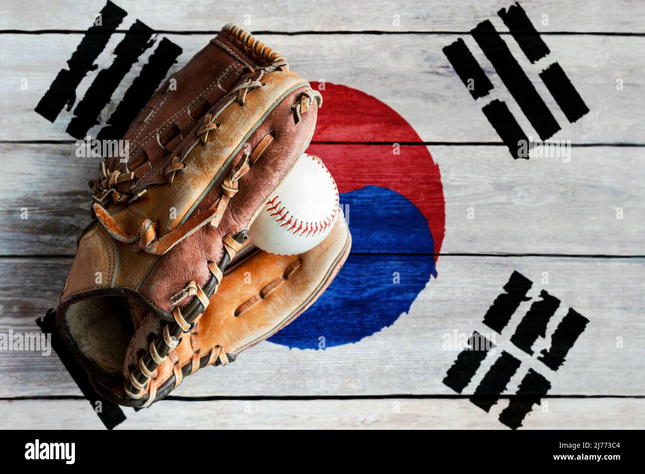 Baseballhandschuh aus Leder mit Ball auf rustikalem Holzhintergrund mit bemalter südkoreanischer Flagge und Kopierraum. Südkorea ist eine der weltweit führenden Stützpunkten Stockfoto