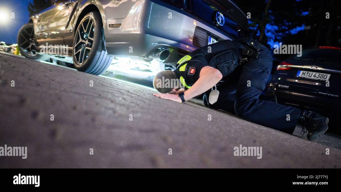 06. Mai 2022, Niedersachsen, Hannover: Polizeibeamte überprüfen im Expo Park ein getuntes Fahrzeug. Am Freitagabend trafen sich wieder Hunderte von Autotunern und Autofans auf dem ehemaligen Expo-Gelände in Hannover. Die Polizei von Hannover kontrollierte zahlreiche Fahrzeuge auf den Zufahrtsstraßen. Foto: Julian Stratenschulte/dpa Stockfoto