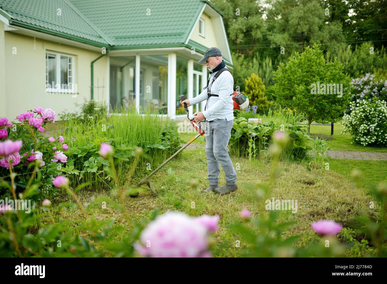 Mann mäht hohes Gras mit Elektro- oder Benzin-Rasentrimmer im Hinterhof.  Werkzeuge und Geräte für die Gartenpflege. Prozess des Rasentrimmens mit  dem Handmäher Stockfotografie - Alamy