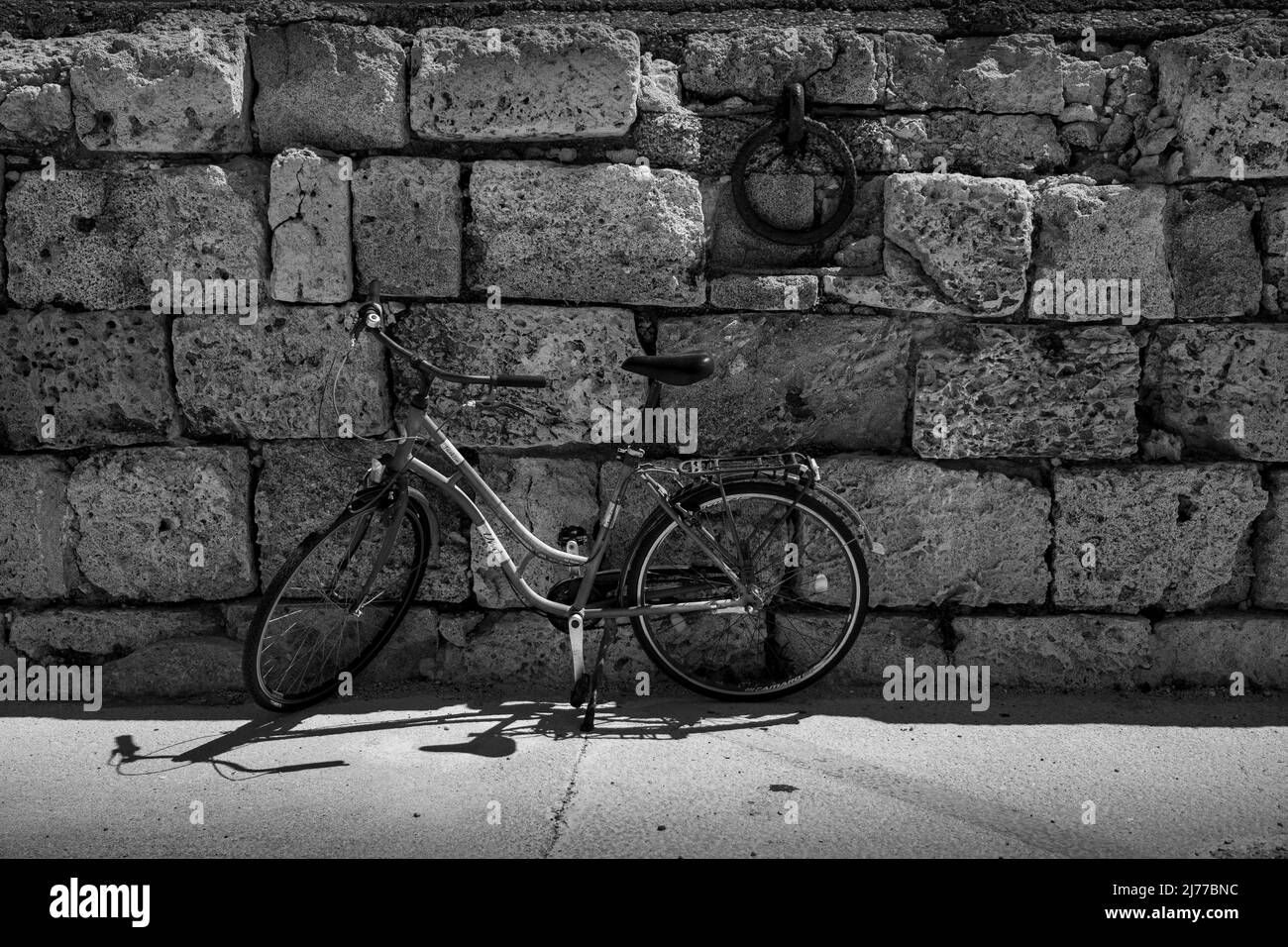 Schwarz-weiß, Fahrradständer gegen eine alte Steinmauer am Hafen. Stockfoto