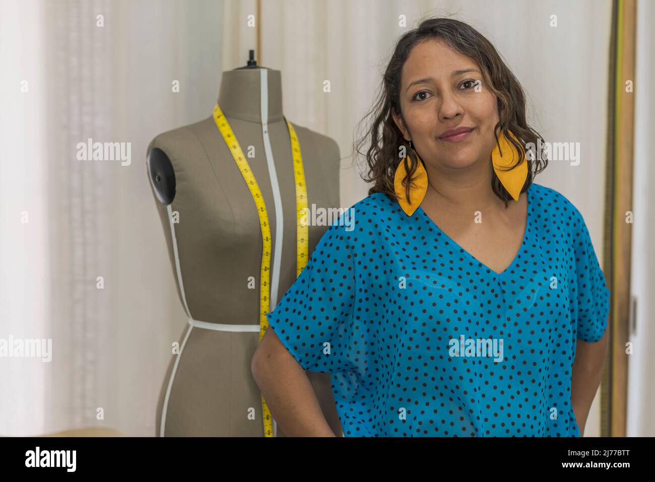 Porträt einer lateinischen Modedesignerin neben einer Schaufensterpuppe Stockfoto
