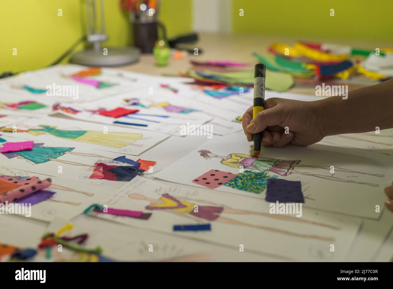 Lateinische Modedesignerin skizziert auf ihrem Schreibtisch mit Markern Stockfoto