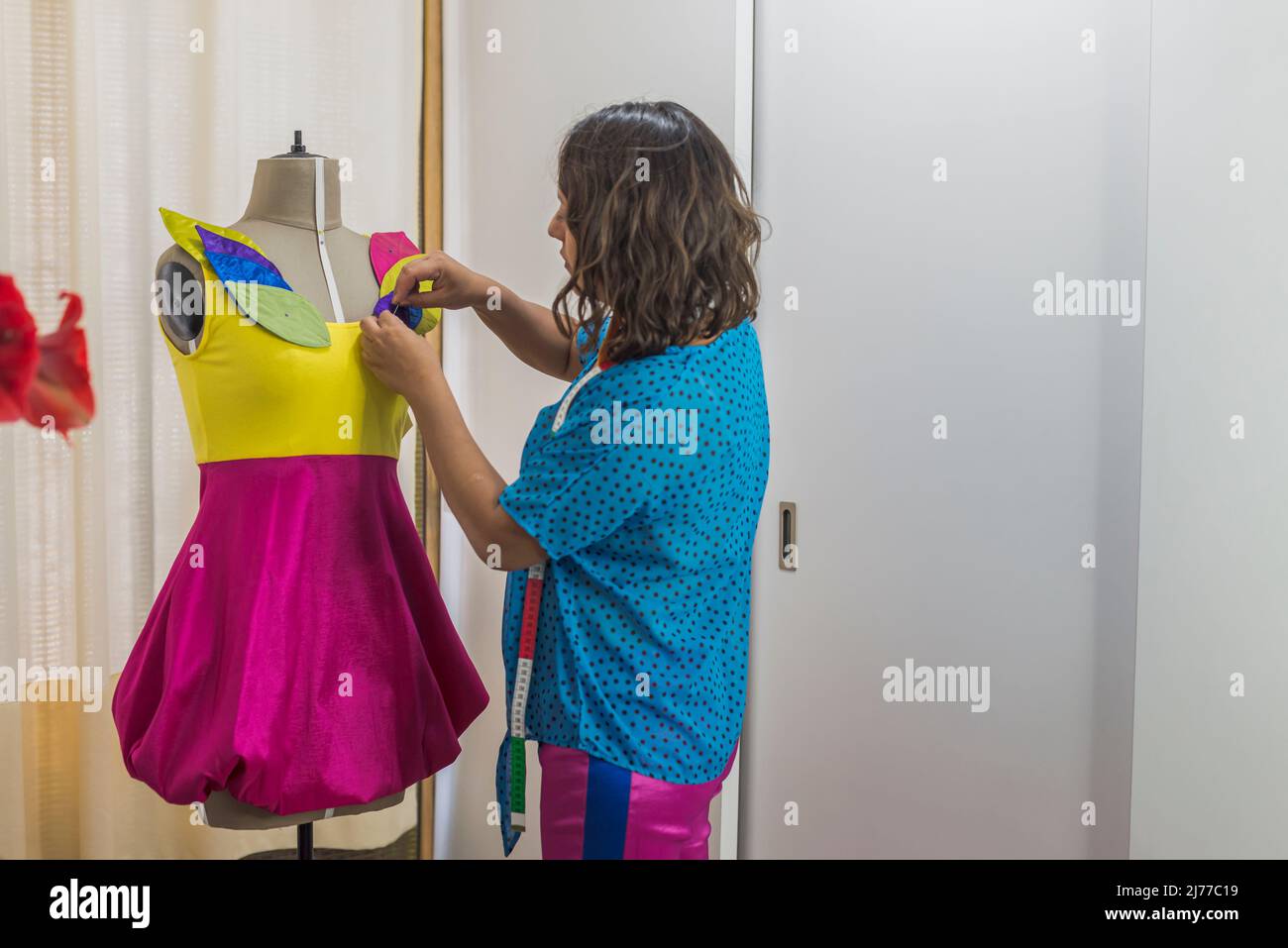 Lateinische Modedesignerin, die an einem Kleid über einer Schaufensterpuppe arbeitet Stockfoto