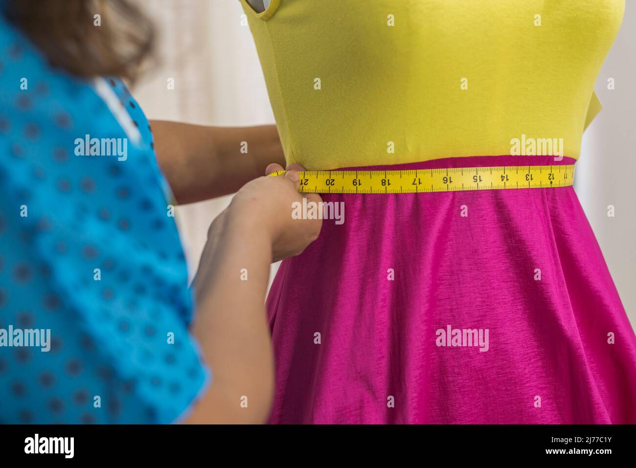 Nahaufnahme eines lateinischen Modedesigners, der ein Kleid mit einem Klebeband misst Stockfoto