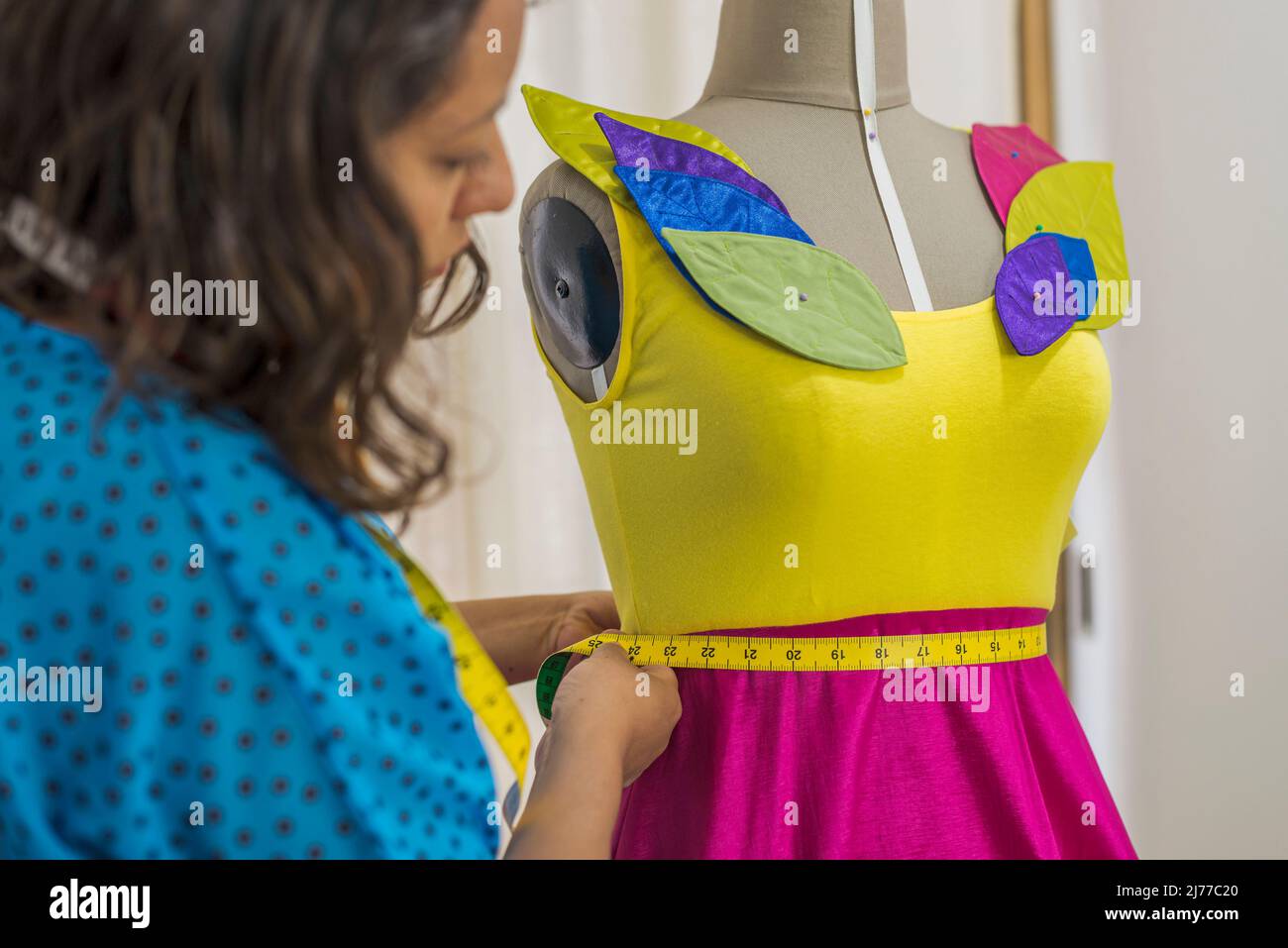 Lateinischer Modedesigner, der ein farbenfrohes Kleid mit einem Klebeband misst Stockfoto