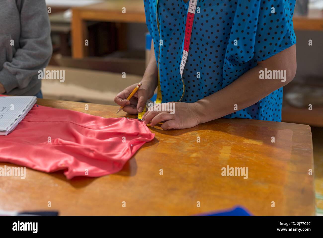 Lateinischer Modedesigner, der ein Kleid mit einem Klebeband auf einem Tisch misst Stockfoto