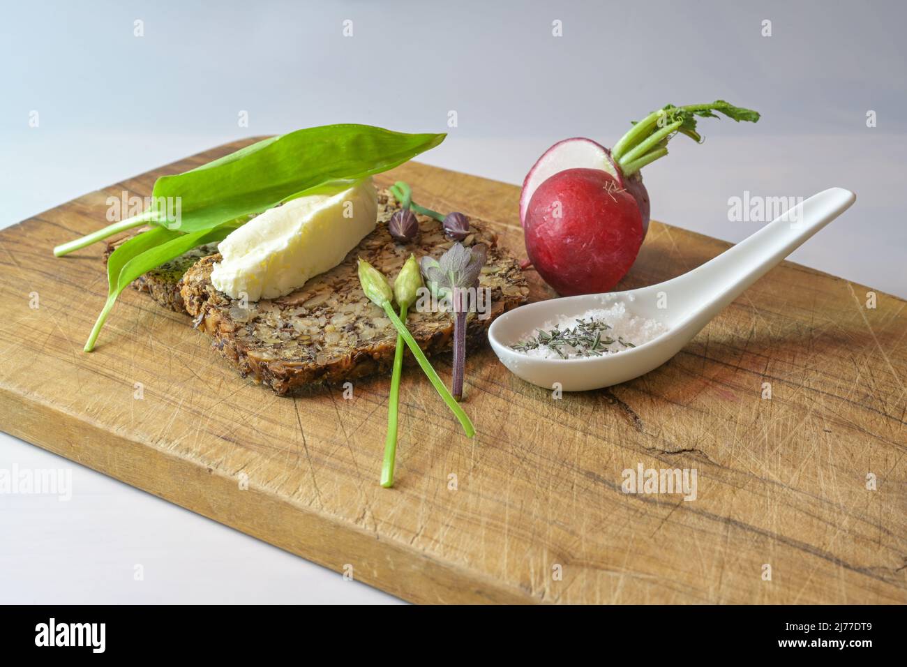 Vollkornbrot mit Butter, Rettich, Kräutersalz und Bärlauch auf einem rustikalen Holzschneidebrett, einfache gesunde und natürliche Mahlzeit, Platz kopieren, auswählen Stockfoto