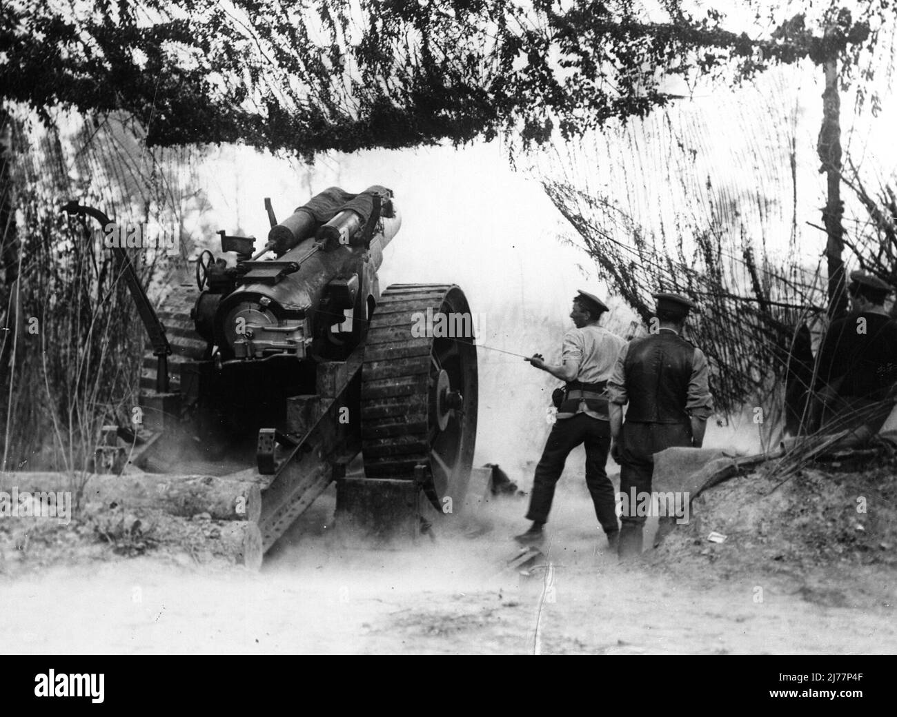 Ein Howitzer, der aus einer getarnten Position in Wagonlieu in der Nähe von Ypern abgefeuert wurde. Einer der Männer verwendet eine sehr lange Stange oder einen sehr langen Kegel, um die Ladung zu entzünden. Die Schlacht am Messines Ridge - 12. Mai 1916 Stockfoto