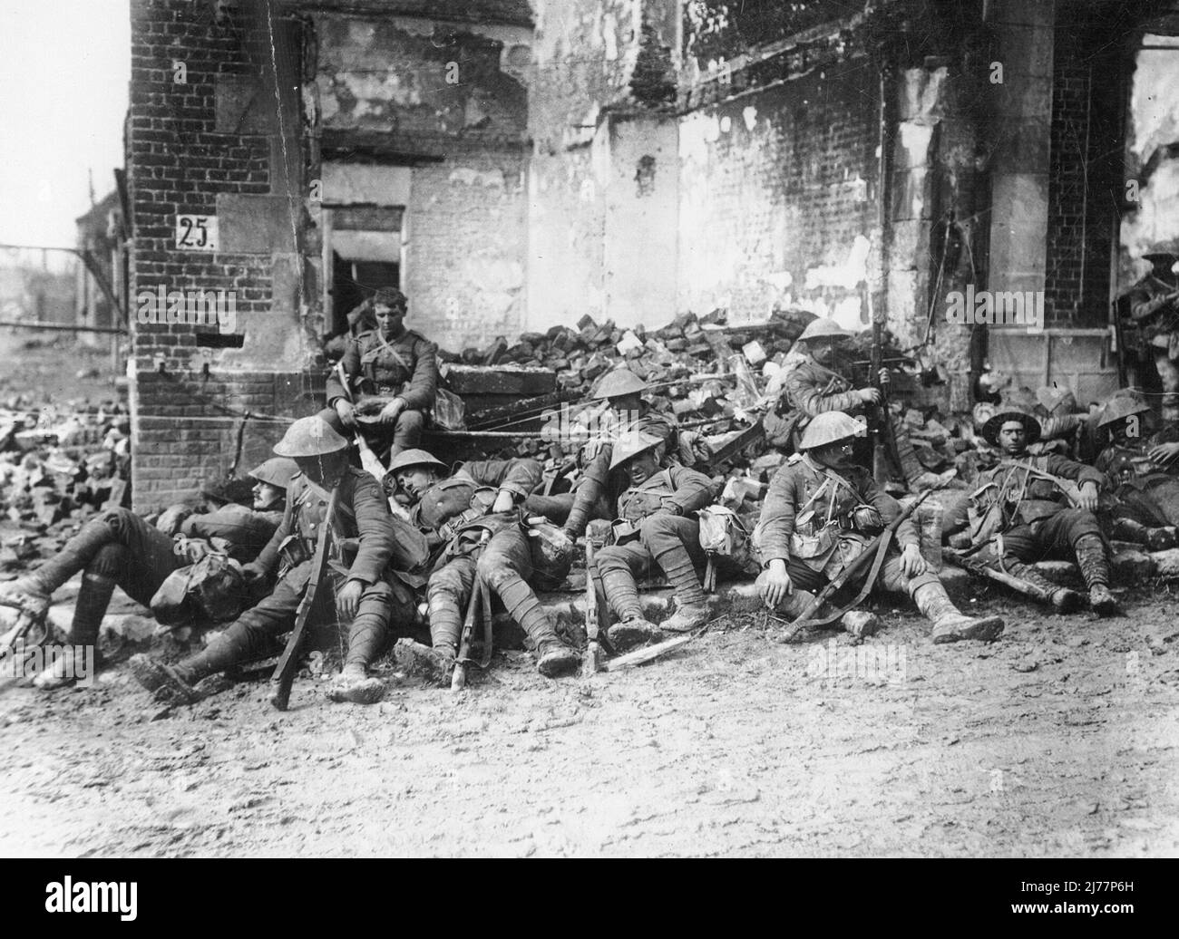 Während des Ersten Weltkriegs ruhende Truppen in Peronne, Frankreich. Soldaten legen sich alle nieder oder schlagen gegen den Boden eines Schutthauses. Sie sind alle voll ausgestattet und bewaffnet. Die meisten von ihnen scheinen zu schlafen. Stockfoto