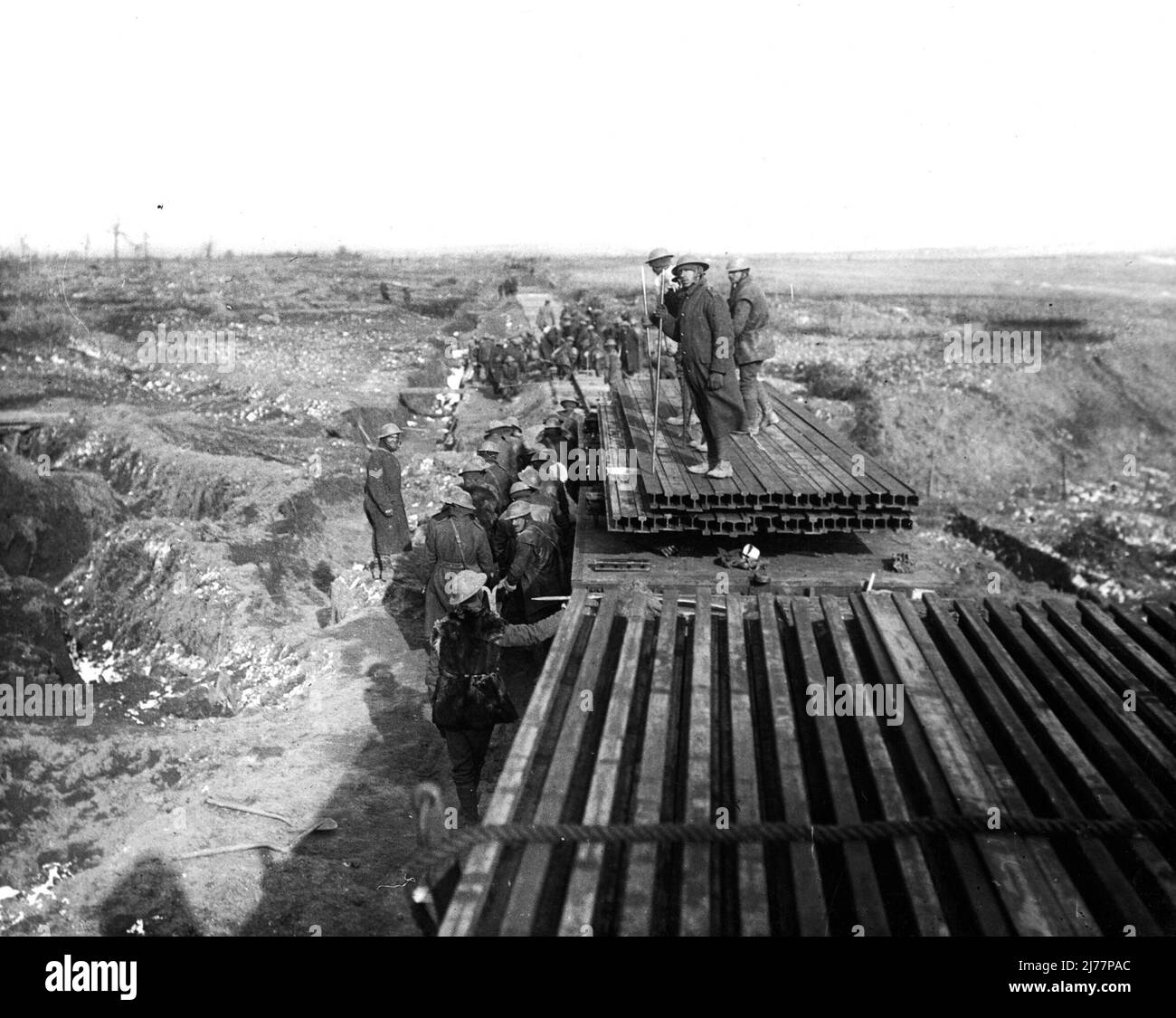 Eisenbahnlinien werden verlegt. Eine Dampfmaschine schlingert Waggons voller Eisenbahnlinien bis zum Ende der bereits verlegten Strecke. Stockfoto