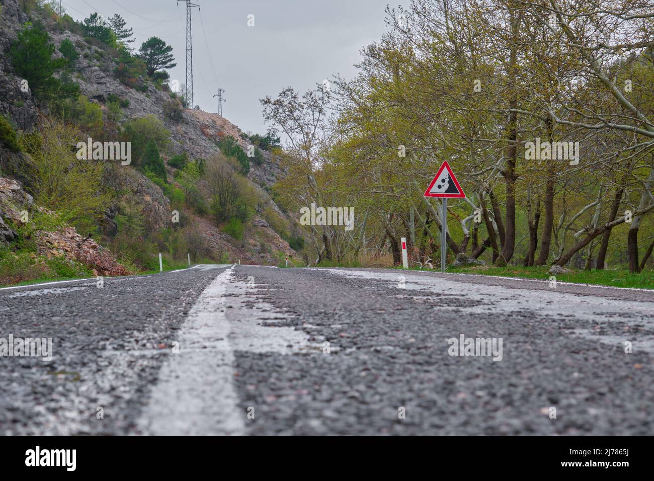 Niederwinkel Straßenlinie Asphalt Weg Foto. Gefährliches Verkehrsschild in der Nähe des Hügels. Stockfoto