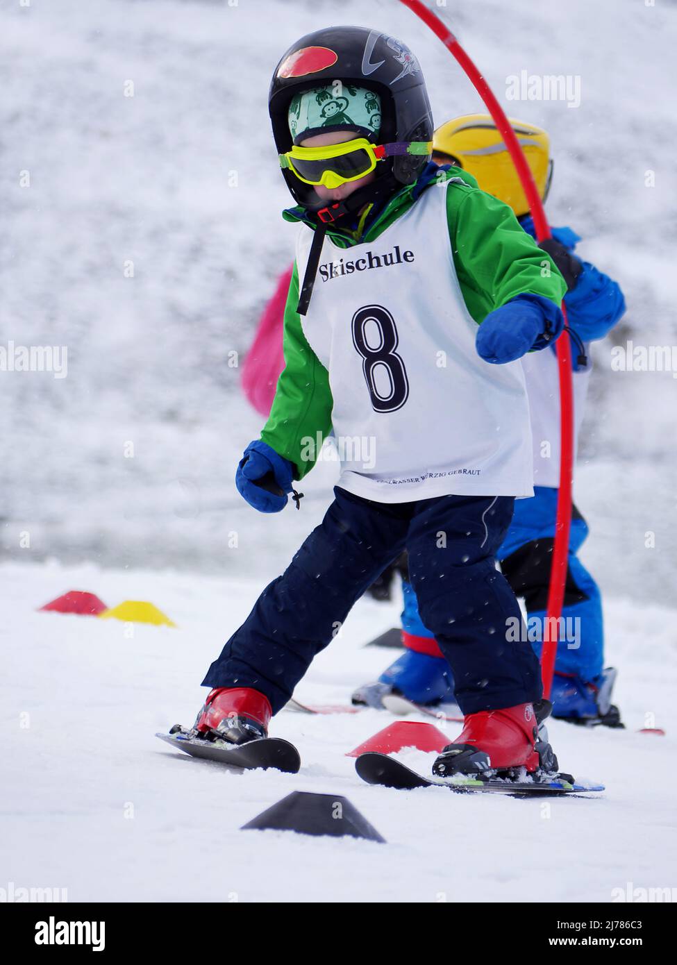 Der 4-jährige Junge lernt die Schneepflug-Wende in einer Skischule, indem er einen Slalom passiert Stockfoto