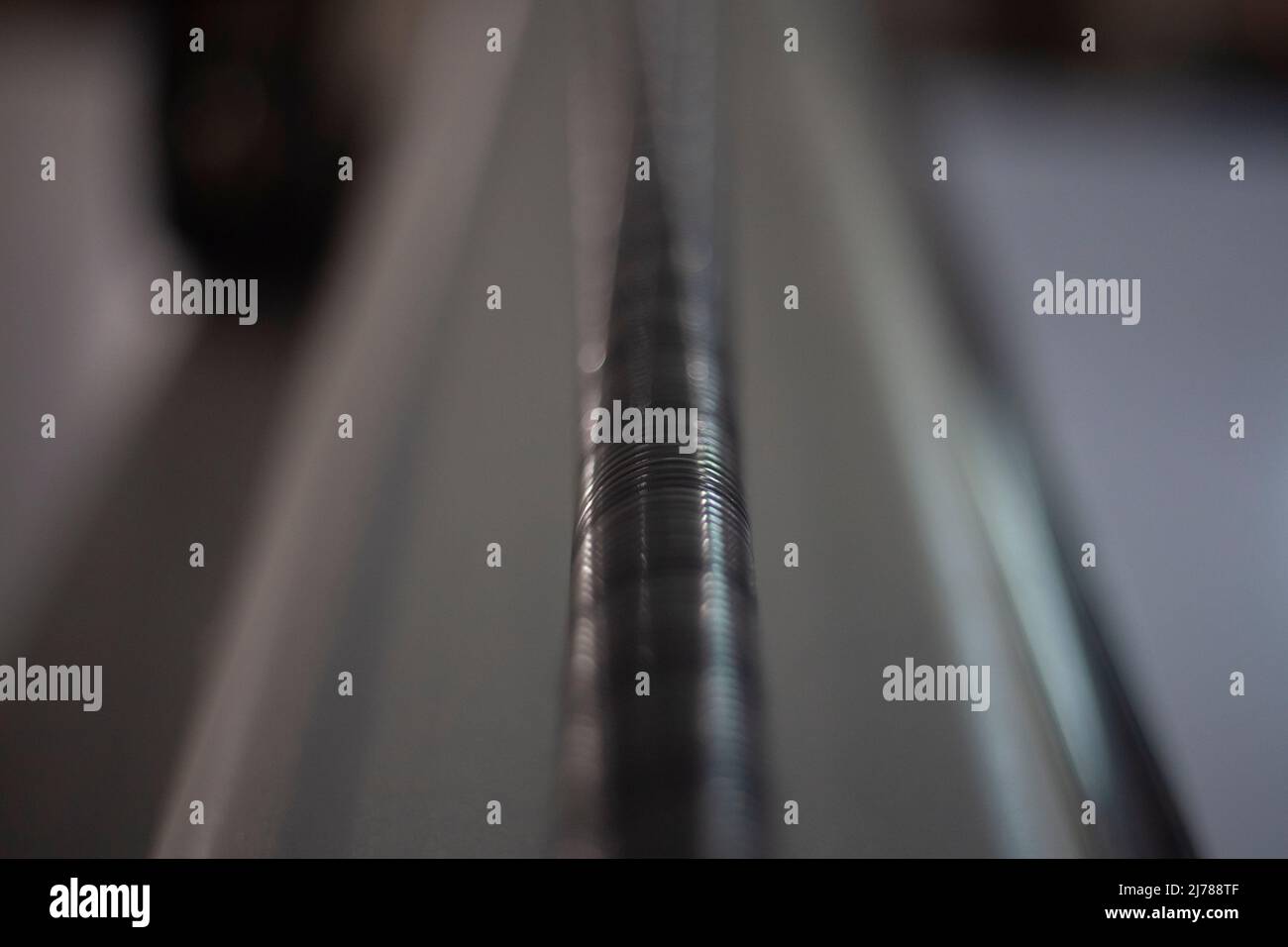 Schnitzen auf der Maschine. Produktionsdetails. Gewindestift. Makrofotografie des Stahlteils. Verschwommener Hintergrund und Fokus auf geringe Schärfentiefe. Verschwinden Stockfoto