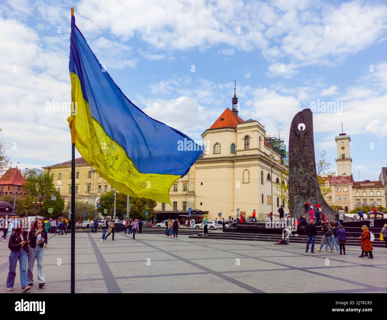 Der Krieg in der Ukraine. Ukrainische Flagge vor dem Hintergrund des Stadtrats von Lemberg und des Denkmals für Taras Schewtschenko Stockfoto