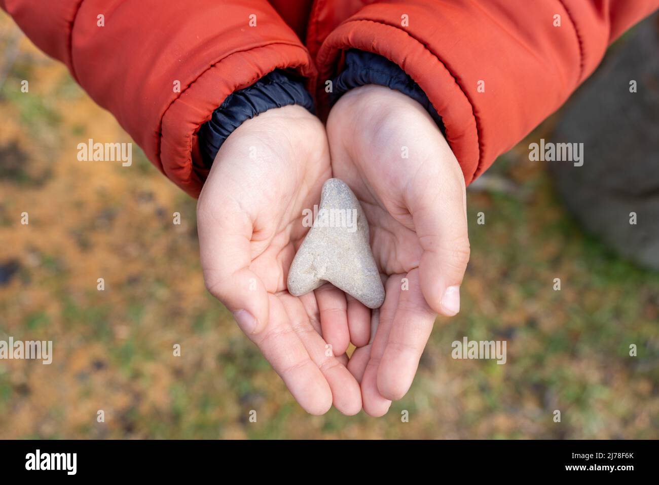 Die Hände des Kindes halten einen herzförmigen Stein aus der Nähe Stockfoto