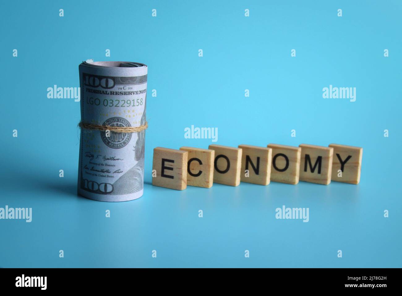 Holzwürfel mit Text ECONOMY und Banknote auf blauem Hintergrund mit Kopierfläche. Stockfoto