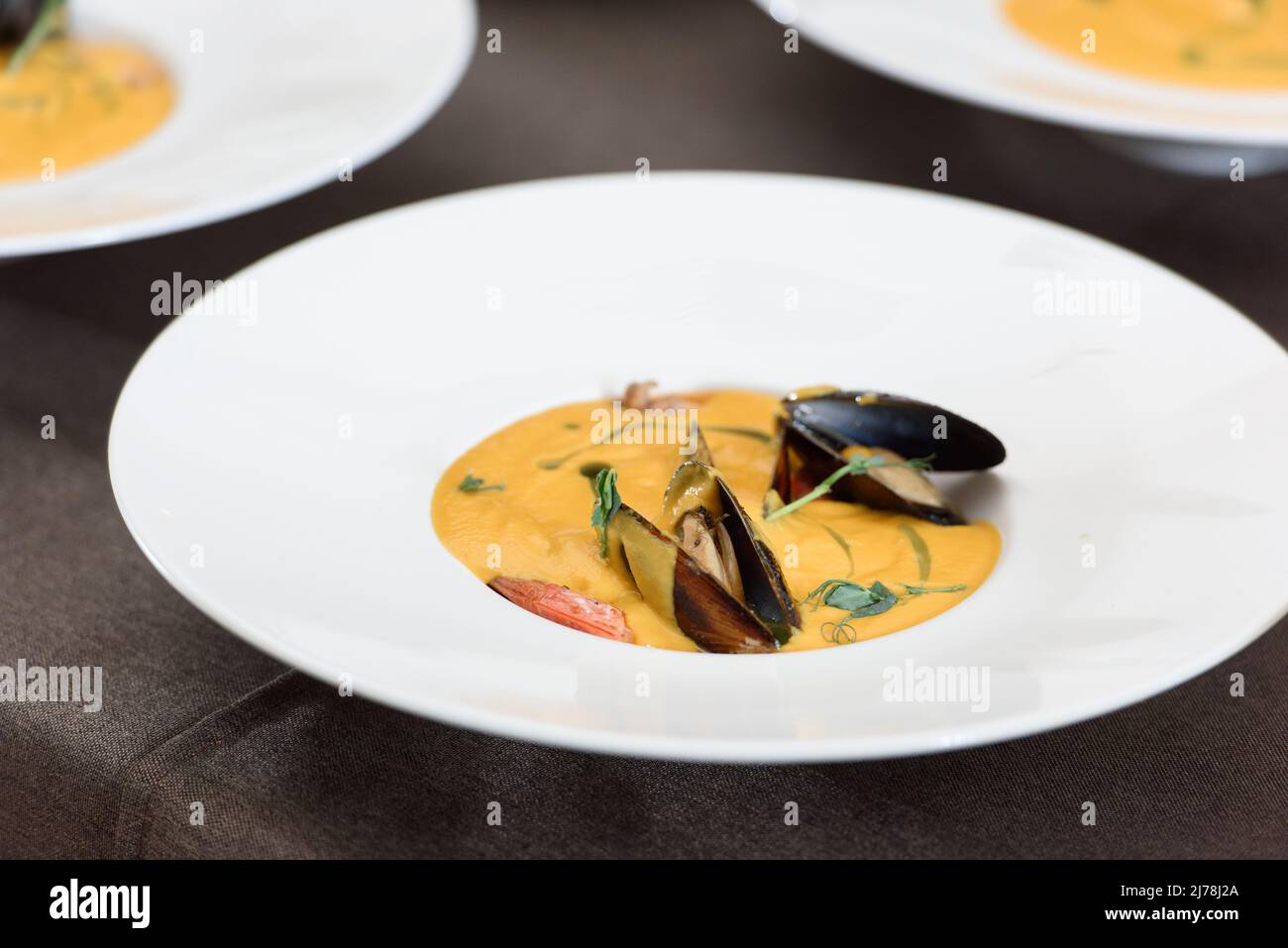 Karotten-Sahnesuppe mit Meeresfrüchten auf einem Tisch in einem Restaurant Stockfoto