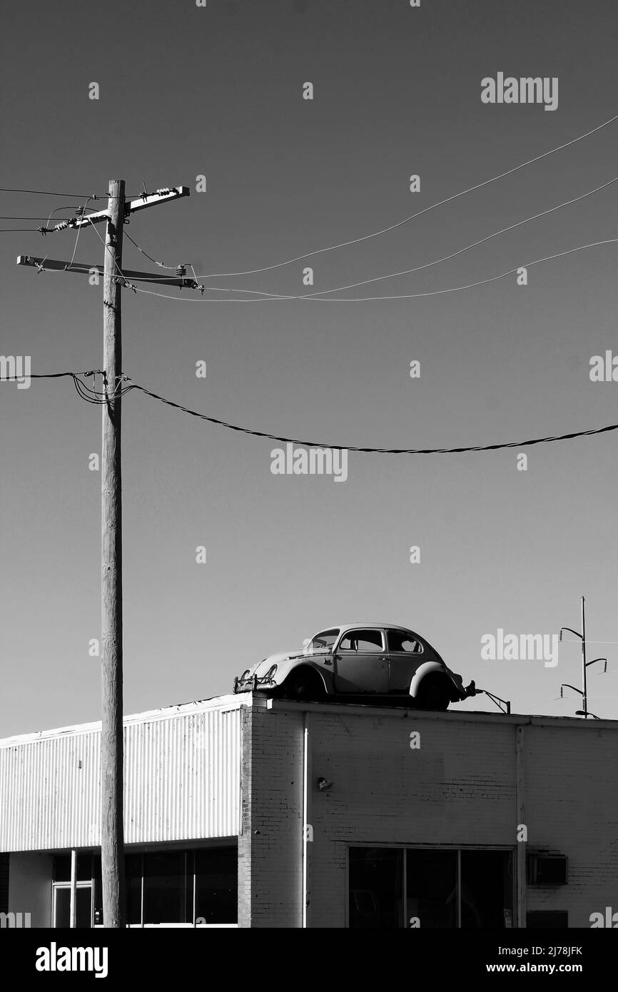 Vintage Volkswagen Käfer klebte auf dem Dach des lokalen Geschäfts in schwarz und weiß. Stockfoto