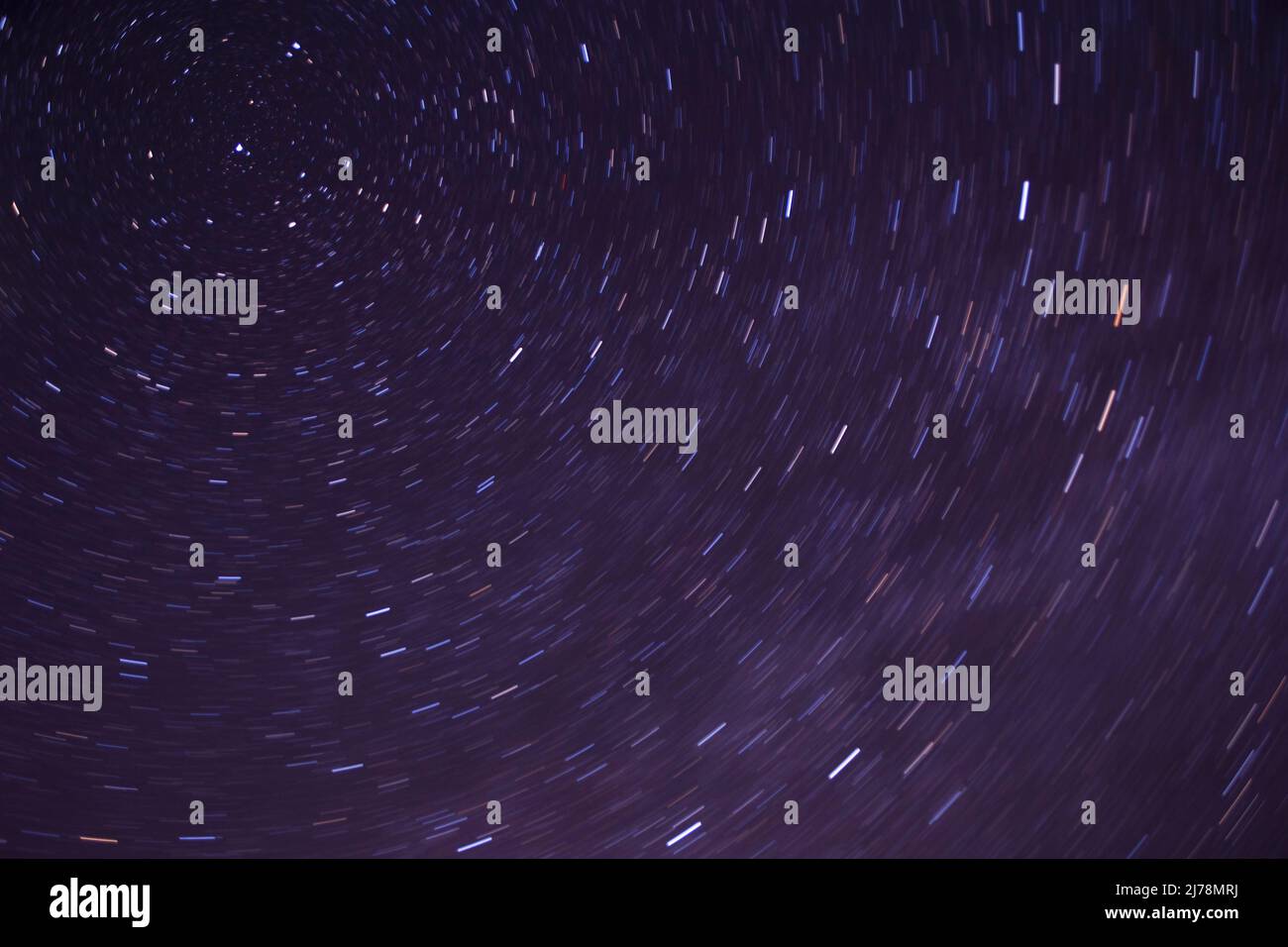 Abstrakter natürlicher Hintergrund: Spuren von Sternen um den Polarstern, die durch die Rotation der Erde verursacht werden Stockfoto