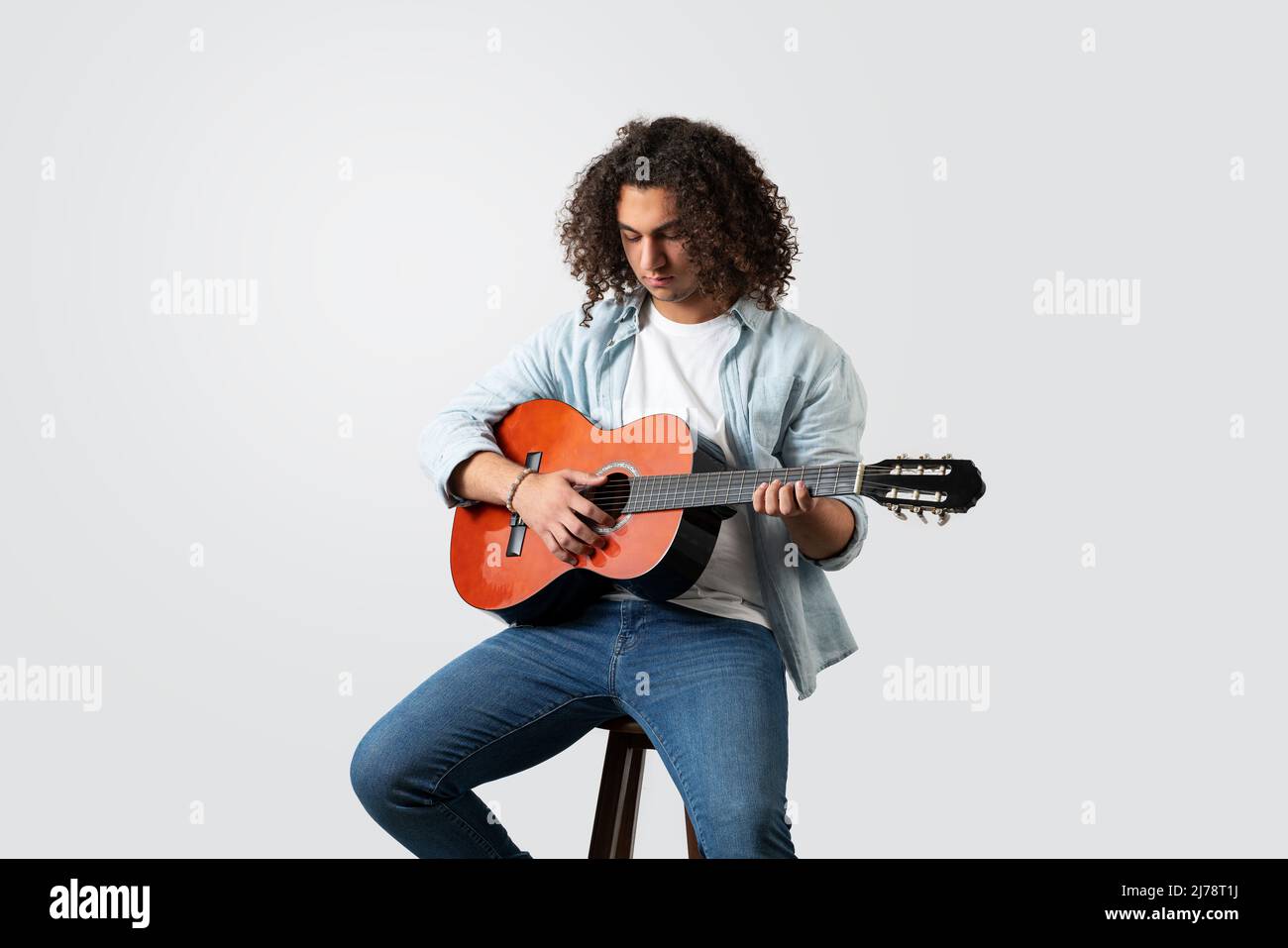 Junger Mann spielt akustische Solo-Gitarre, isoliert auf weißem Hintergrund. Hochwertige Fotos Stockfoto