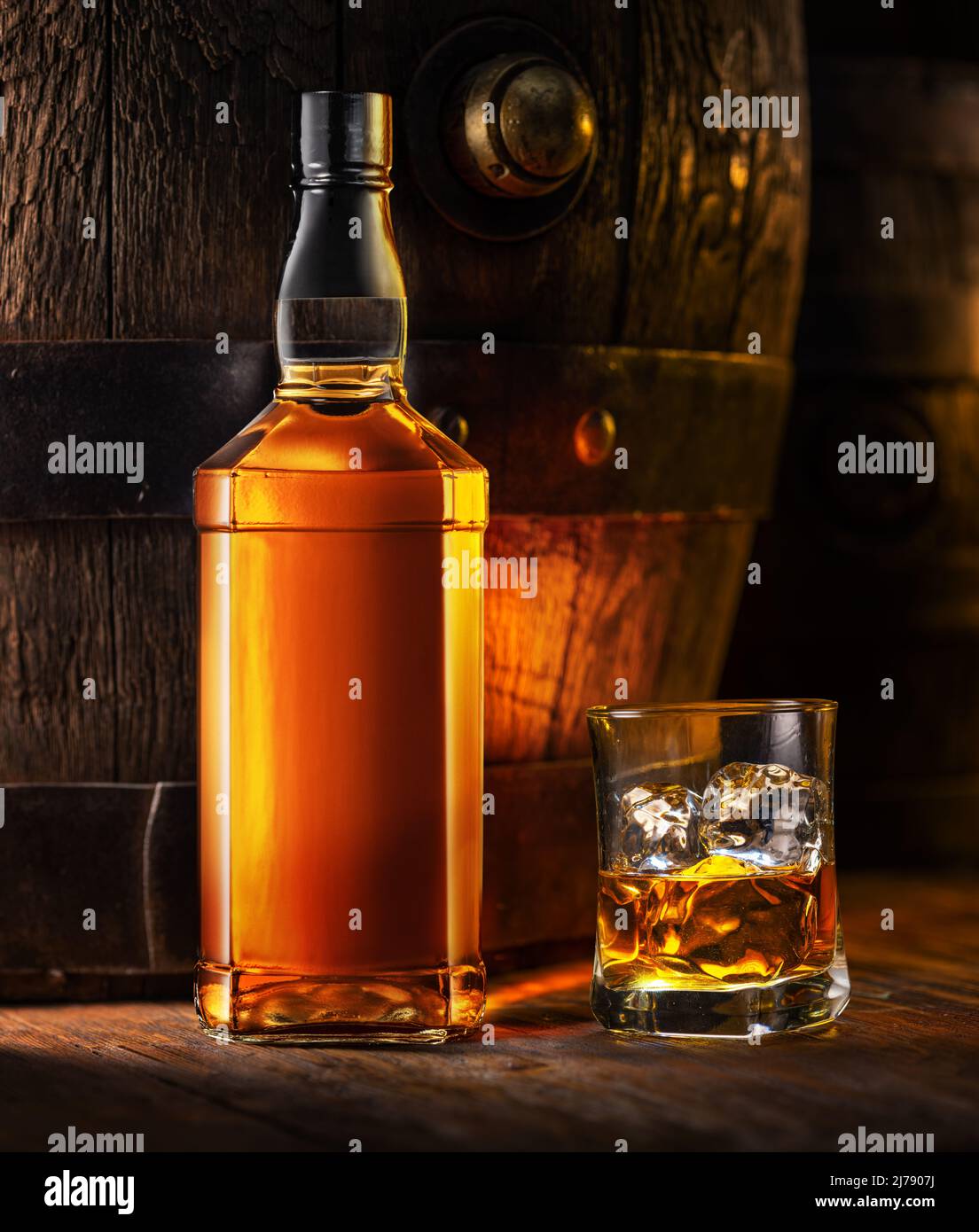 Whisky-Flasche und ein Glas Whisky. Altes Holzfass im Hintergrund. Stockfoto