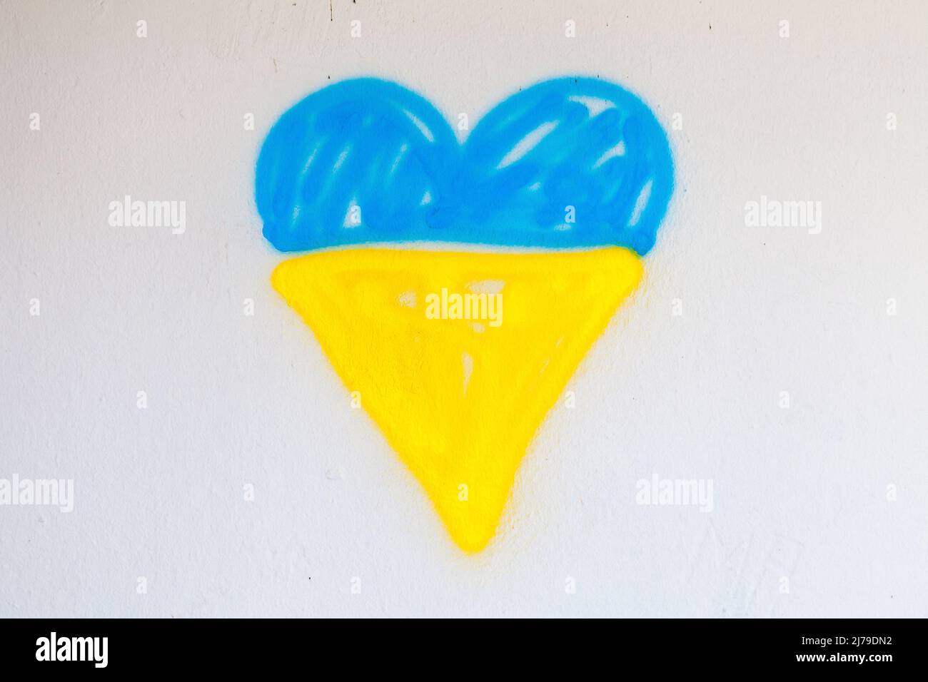 Besprühen Sie das bemalte Herz mit der ukrainischen Flagge. Stockfoto