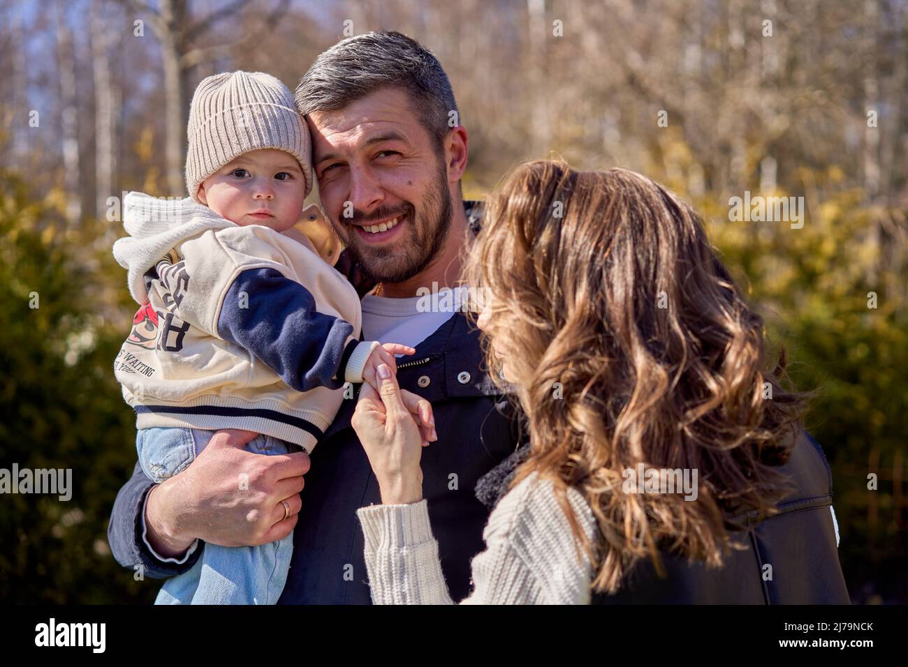 Eine Familie mit kleinem Baby. Vater hält Tochter an den Händen. Baby beim Betrachten der Kamera. Mutter hält die Hand des Kindes. Stockfoto