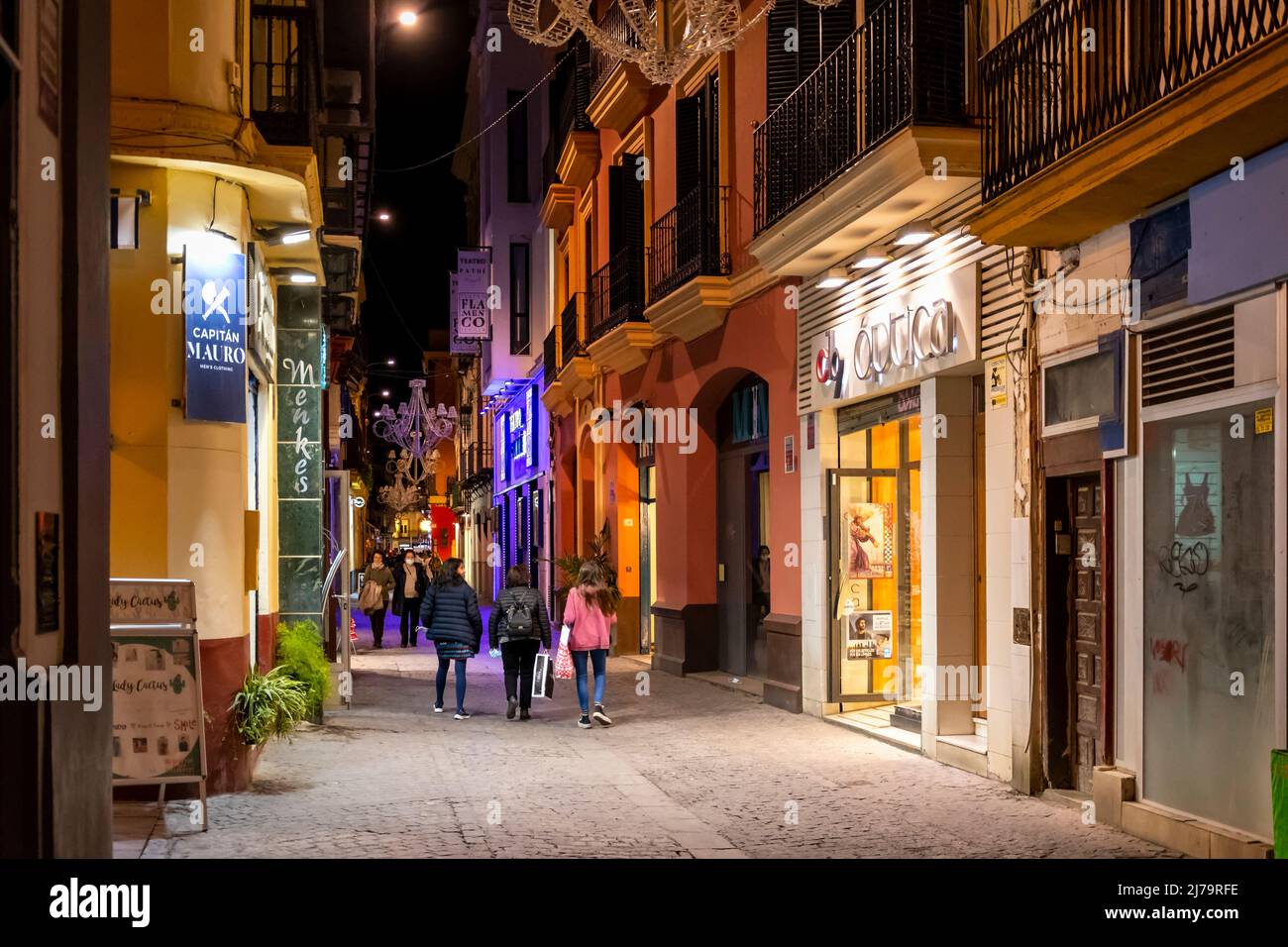 Geschäfte und Cafés beleuchtet am Abend im Viertel Barrio Santa Cruz im historischen Zentrum der andalusischen Stadt Sevilla, Spanien. Stockfoto