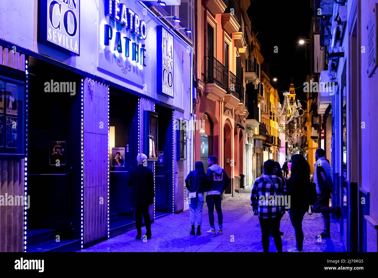 Geschäfte und Cafés beleuchtet am Abend im Viertel Barrio Santa Cruz im historischen Zentrum der andalusischen Stadt Sevilla, Spanien. Stockfoto