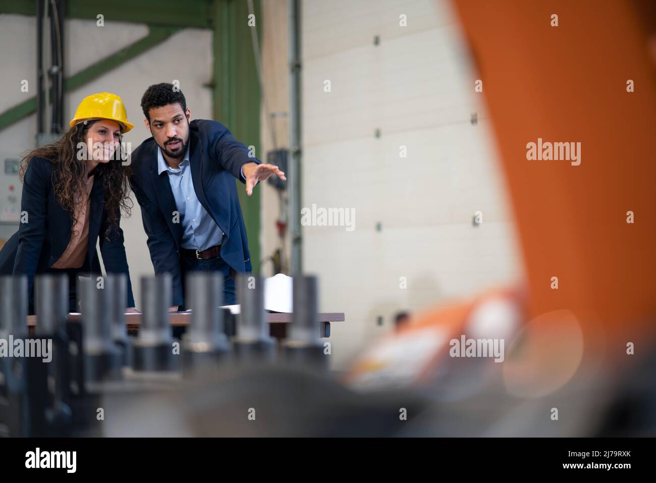 Ein Ingenieur, der seinem Kollegen in der industriellen Roboterfabrik Maschinen zeigt. Stockfoto