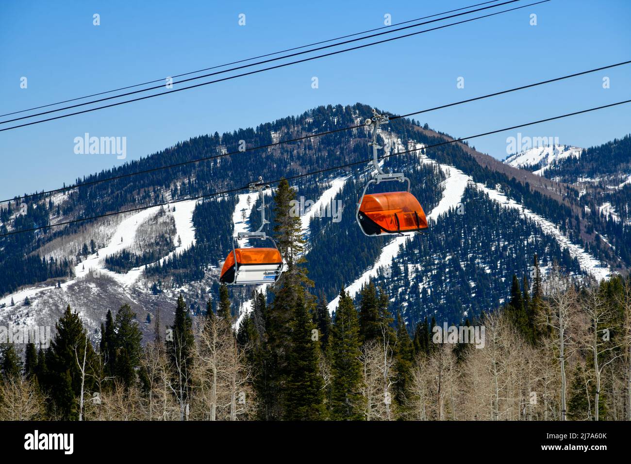 Orange Bubble Chair Lift im Park City Canyons Skigebiet in Utah. Spätfrühlingswetter. Blick auf die Berge mit Skipisten. Stockfoto