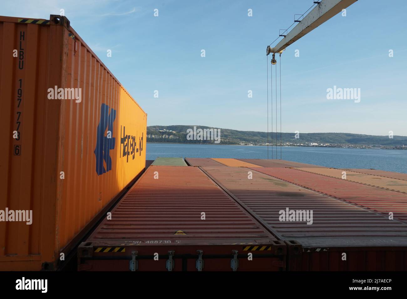Oranger Container von Hapag Lloyd Reederei wird auf der obersten Ebene im hinteren Teil des Containerschiffes mit Kränen verladen verlassen Hafen von Koper Slowenien. Stockfoto
