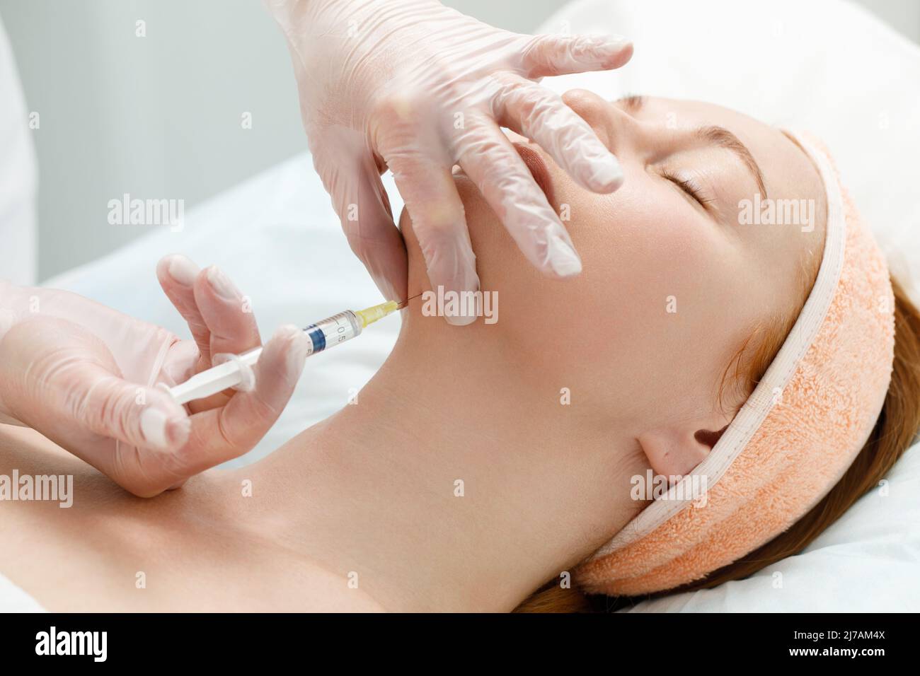 Der Kosmetologe führt das Kinnlift-Verfahren durch Injektionen von Schönheitsinjektionen durch. Arzt injiziert Hyaluronsäure in das ching einer Frau als Gesichtsbehandlung Stockfoto