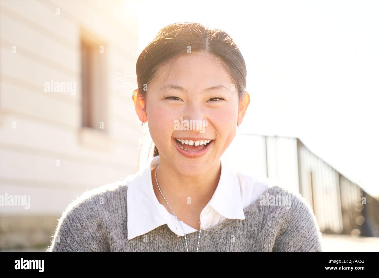 Außenportrait eines lächelnden chinesischen Mädchens, das mit positivem Gesicht und freundlichem Blick auf die Kamera lacht. Nahaufnahme eines glücklichen menschlichen Gesichts - Stockfoto