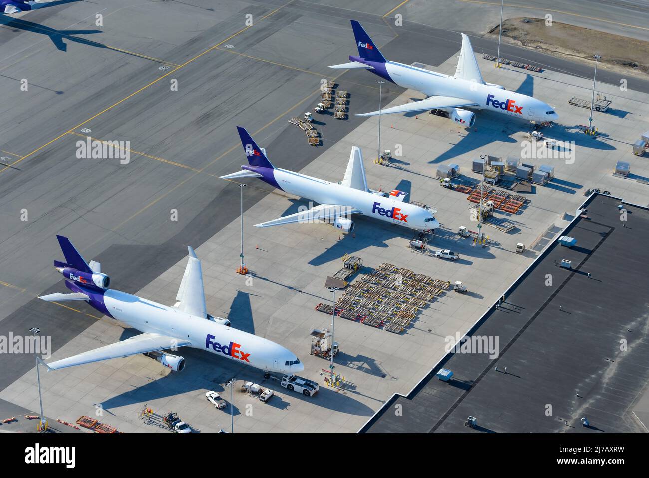 Flugzeuge von FedEx Cargo am Flughafen Anchorage, einem Drehkreuz für den Güterverkehr des Federal Express. Line-up von Frachtschiffflugzeugen und Paletten. Stockfoto