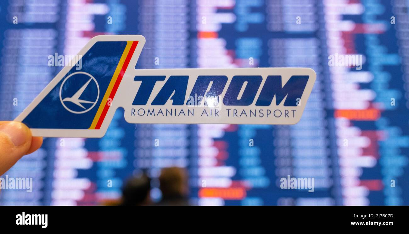 11. Dezember 2021, Bukarest, Rumänien. Das Emblem der Fluggesellschaft TAROM vor dem Hintergrund einer elektronischen Tafel mit einem Flugplan auf der int Stockfoto