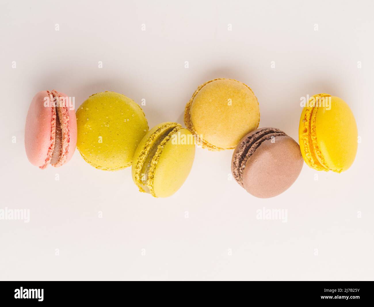 Französische pastellfarbene Makronen bei einem gefrorenen Flug auf weißem Hintergrund. Festliche Komposition. Geburtstag, romantische Datum, süße Lebensmittel, Kalorien. Werbung Stockfoto