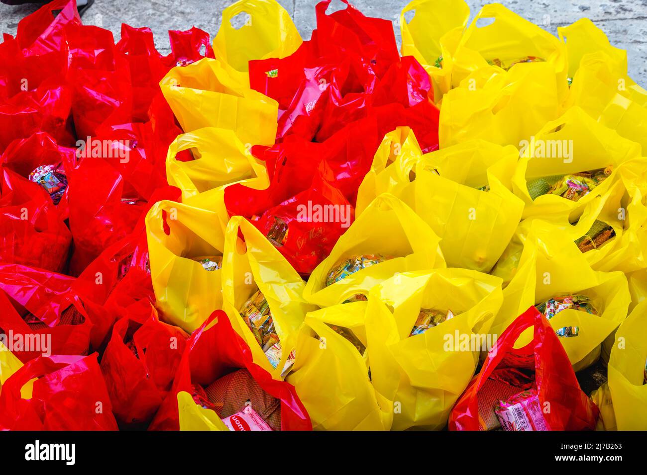 Rote und gelbe Kunststoffbeutel füllen den Rahmen mit nach oben hängenden Griffen. Spenden für die Armen in Vietnam. Stockfoto