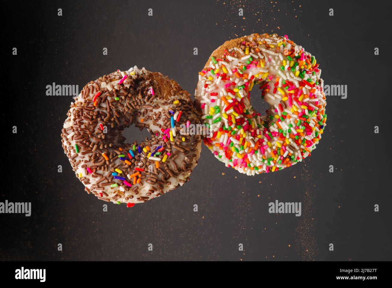 Zwei Donuts in einem gefrorenen Flug auf grauem Hintergrund. Süßes Essen, Happy Hormone, amerikanisches Frühstück, Fast Food. Werbung, Banner, Geburtstagseinladung Stockfoto