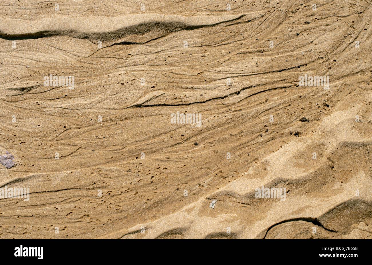 Sand erhält ein entzückendes Design, nachdem sich die Wellen und der Wind verschlängeln. Stockfoto